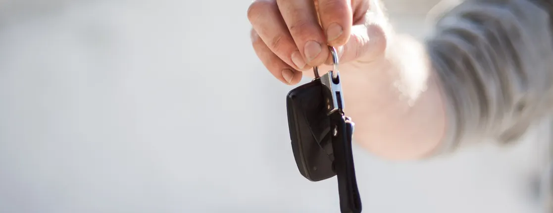Een hand houdt een autosleutel met sleutelhanger omhoog